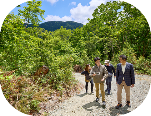 整備された山道を話ながら歩いている3名の男性と1名の女性の風景。