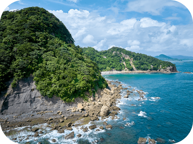 青空と青い海。波打ち際に岩場や山が見えています。